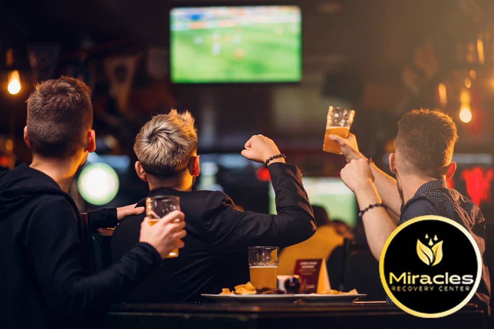 men sit at a bar drinking and watching football