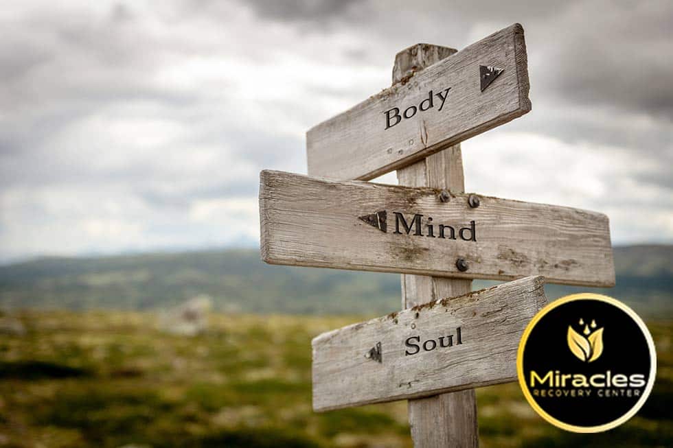 wooden sign on a mountainside showing three categories of self-care body mind soul